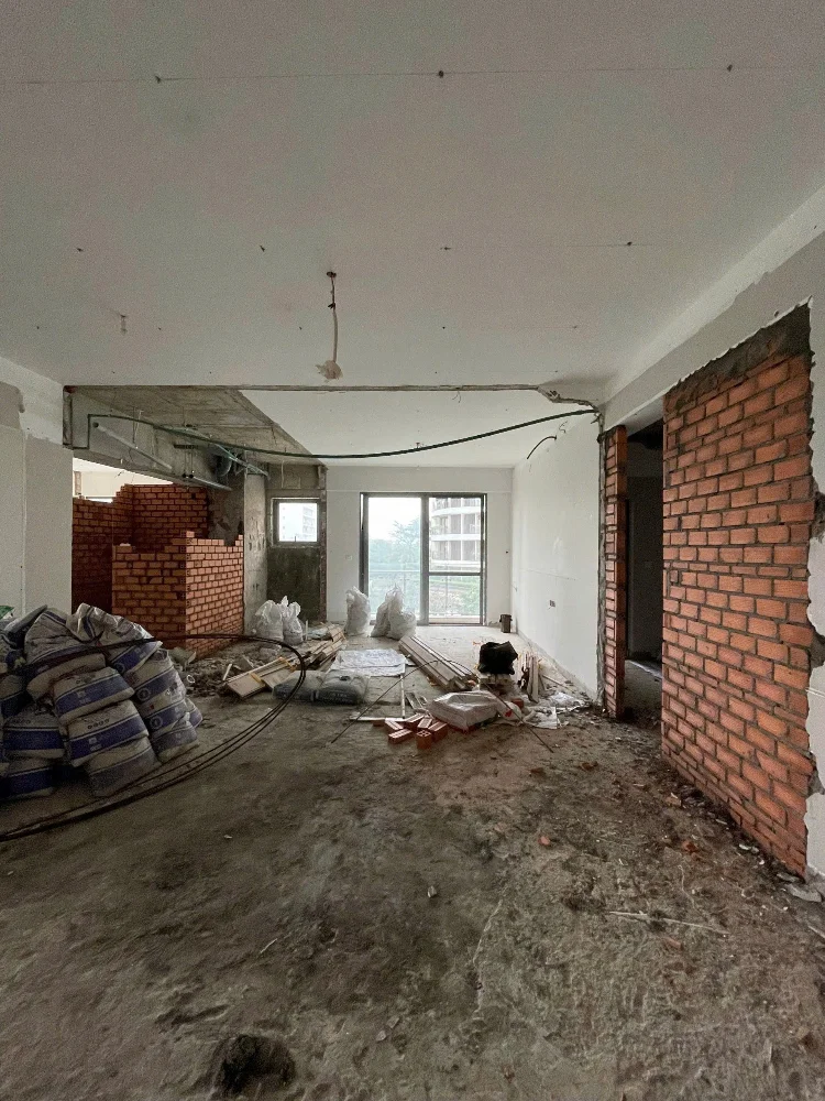 Hiện trạng căn hộ đang cải tạo với tường gạch xây mới, bao xi măng và dây điện treo trên trần